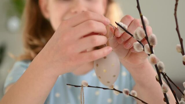 Close up video of girls hands hanging easter eggs on willow branch