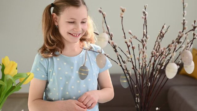 Close up video of girls hands hanging easter eggs on willow branch