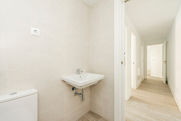 Fototapeta na wymiar bathroom with white porcelain sink, hardwood floors in a long hallway with access to other rooms