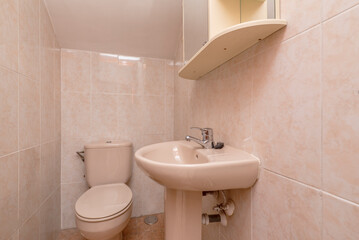 Small pink-toned sink under a stairwell