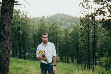 Wide shot of adult male standing with wild flowers black hills