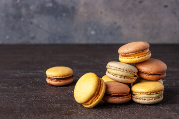 french macaroon dessert lie on brown texture background, copy sp