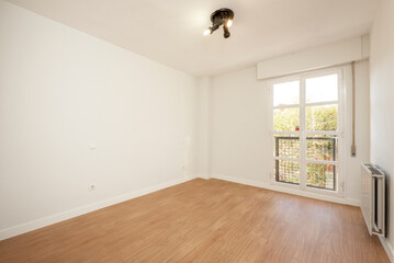 Empty room with a bay window, white aluminum radiator and wooden floors