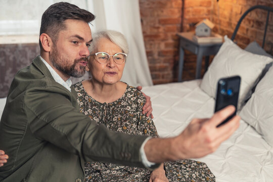 short-haired grandmother and her bearded grandson making duck face and taking a selfie during Grandmother's Day Grandparent's Day. High quality photo