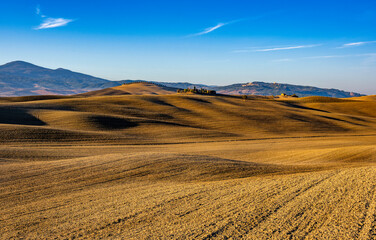Fototapeta na wymiar Beautifully plowed wheat fields with the farmhouse on the hill in Tuscany, Italy