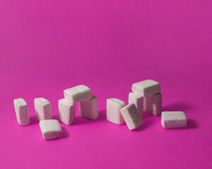 Marshmallows on pink background. Creative sweets composition. Minimalistic sugar concept. Funny Stonehenge idea.