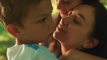 Fond mother kissing boy on picnic close up. Happy woman showing love children. - Powered by Adobe
