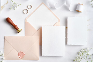Wedding stationery set. Flat lay wedding invitations, pastel pink envelopes, wax seal stamp, golden...
