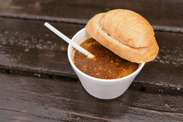 Goulash soup with bread outside in a plastic cup.