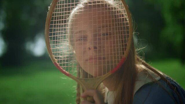 Jjoyful girl making funny faces with badminton racket in summer park closeup.