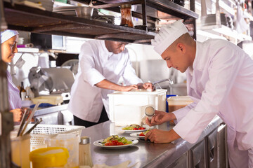 Fototapeta na wymiar Portrait of professional responsible chef during carrying out daily duty in restaurant kitchen