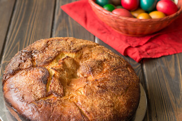 Kozunak (Traditional Easter homemade sweet bulgarian bread) and colored eggs in a red wicker basket on a table of wooden planks