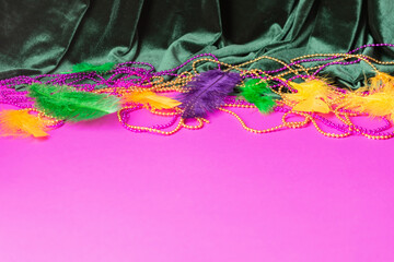Festive carnival background, green velvet curtain colorful feather beads necklace for Mardi Gras 