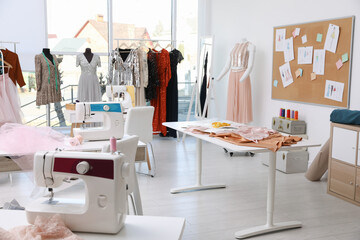 Dressmaking workshop interior with stylish female clothes and equipment