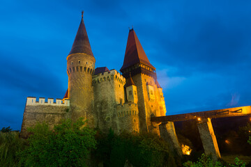 Fototapeta premium Impressive night landscape with illuminated medieval Corvin Castle on elevated rock, Hunedoara, Romania