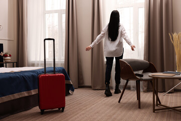 Beautiful businesswoman near window in hotel room, back view