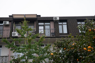 The top floor of the facade of a boarding house with balconies against a cloudy sky.