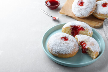 Delicious donuts with jelly and powdered sugar on light grey table. Space for text