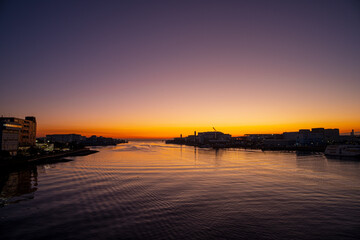 橋から眺める日の出前の朝焼けの海と工場の風景
