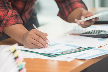 A businessman analyzing investment charts at workplace and using laptop and touch tablet.