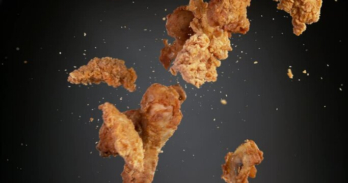 Super slow motion of flying fried chicken pieces hitting in the air, isolated on black background. Filmed on high speed cinema camera, 1000fps.
