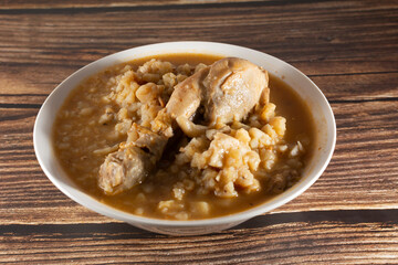 Chicken carapulcra (dry potato) in a deep plate on a wooden background