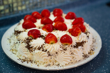 cake decorated with whipped cream and fresh strawberries. homemade dessert.