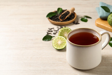 Cup of tasty bergamot tea on white wooden table, space for text
