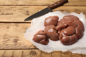 Fresh raw kidneys on wooden table, space for text