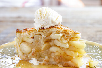 A delicious slice of warm, freshly baked apple pie is ready to eat, including an scoop of vanilla...
