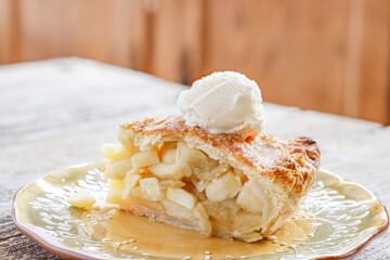 A delicious slice of warm, freshly baked apple pie is ready to eat, including an scoop of vanilla ice cram on top. 