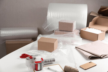 Table with boxes, bubble wrap and packaging equipment in warehouse