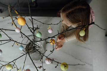 happy caucasian toddler girl eight years old at home in living room with colored easter eggs. Stay home during Coronavirus covid-19 pandemic