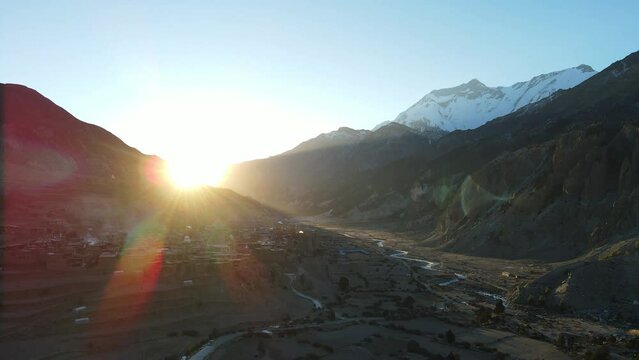 Sun peaking over the mountains flying over Manang Nepal viewing snow capped mountains.