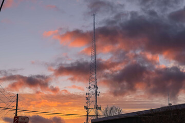 Fototapeta na wymiar a tall gray radio tower surrounded by brown and bare winter trees with blue sky and powerful clouds at sunset in Douglasville Georgia USA