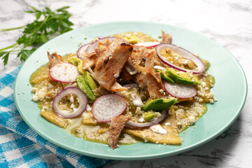 Green chilaquiles with pork meat and cheese. Mexican food
