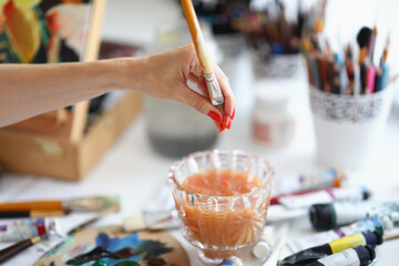 A woman artist squeezes out water from paintbrush