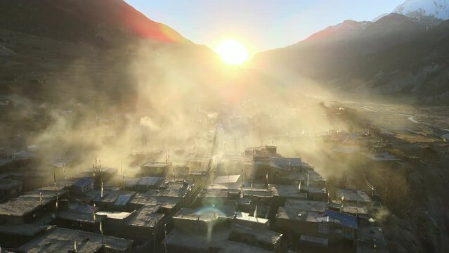 Flying over the village of Manang towards the sunset through smokey haze in Nepal.