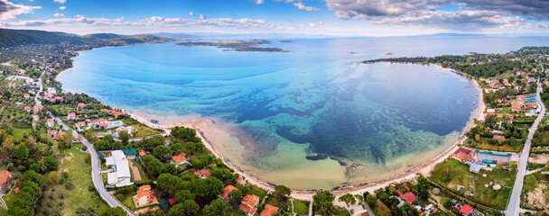 Aerial panoramic scenic view of azure blue lagoon and paradise bay with majestic patterns on a sea shelf. Resort village of Vourvourou on Sithonia peninsula in Halkidiki, Greece