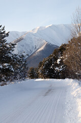 Winter landscape. Snow-covered road to mountain peaks.