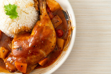 chicken stew with tomatoes, onions, carrot and potatoes on plate with rice