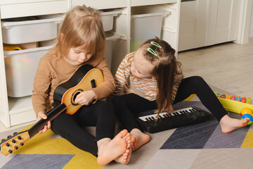 Happy children playing musical instruments at home. Sisters have fun in the room