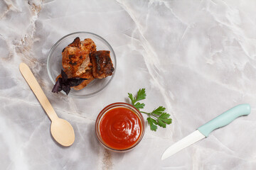 Grilled pork in a bowl with sauce and greens.