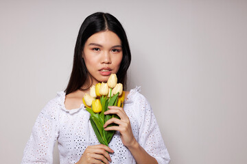 Charming young Asian woman romance bouquet of flowers near the face light background unaltered