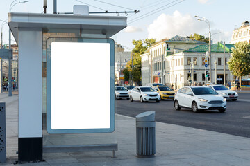 Blank billboard at the bus stop. Many cars are driving along the road. Mock-up.