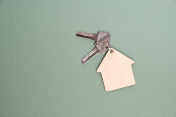 Keychain in form house with keys green background.Concept buying house, apartment or rent.