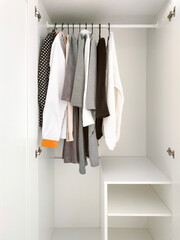 Wardrobe with basic clothes in room scandi interior. Neutral colors: white, black, beige.