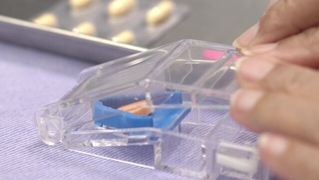 Elderly woman using pill splitter or pill cutter .