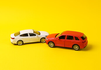 Two mini toy car crash on a yellow background, incident, car traffic accident
