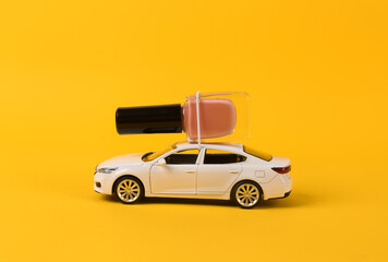 Toy car with bottle of nail polish on yellow background